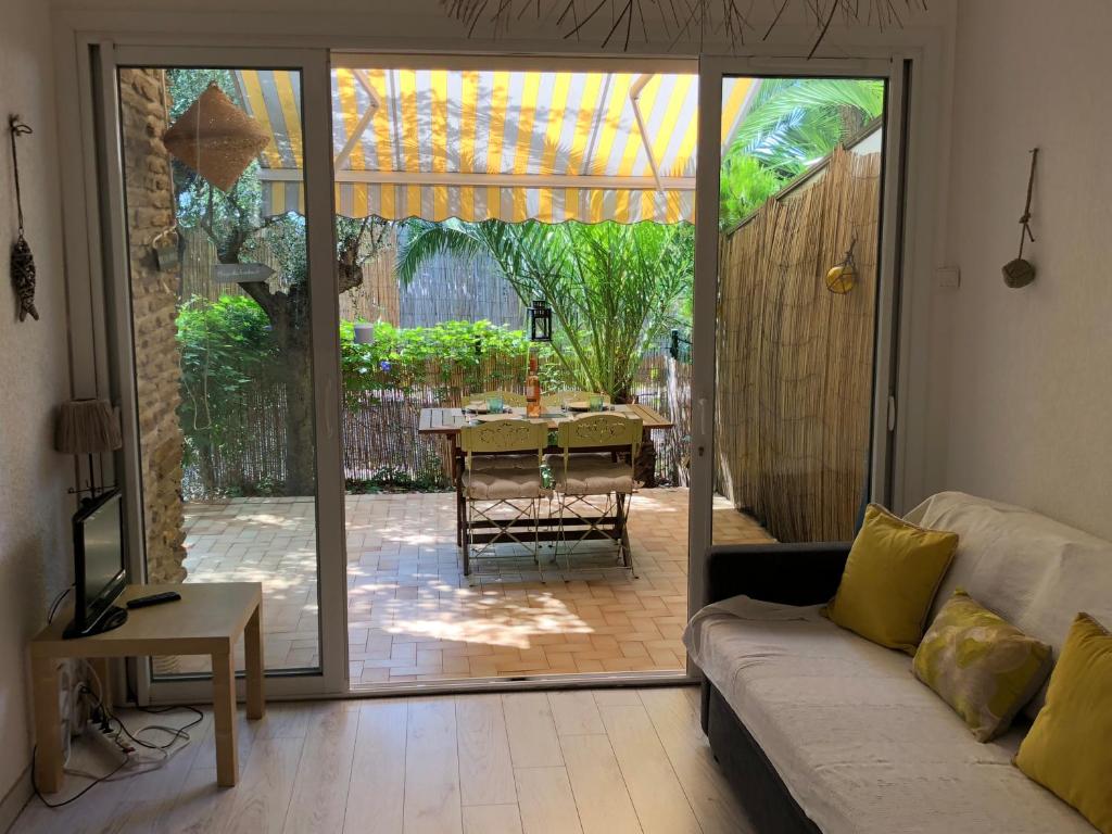 uma sala de estar com uma porta de vidro deslizante que leva a um pátio em **** Beau T2 de 40 m2, jardin de 70m2, au calme, à 50 mètres de la plage em Le Pradet