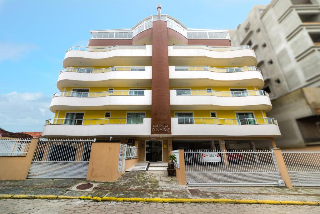 un grand immeuble avec une clôture devant lui dans l'établissement Residencial Dona Naime, à Bombinhas