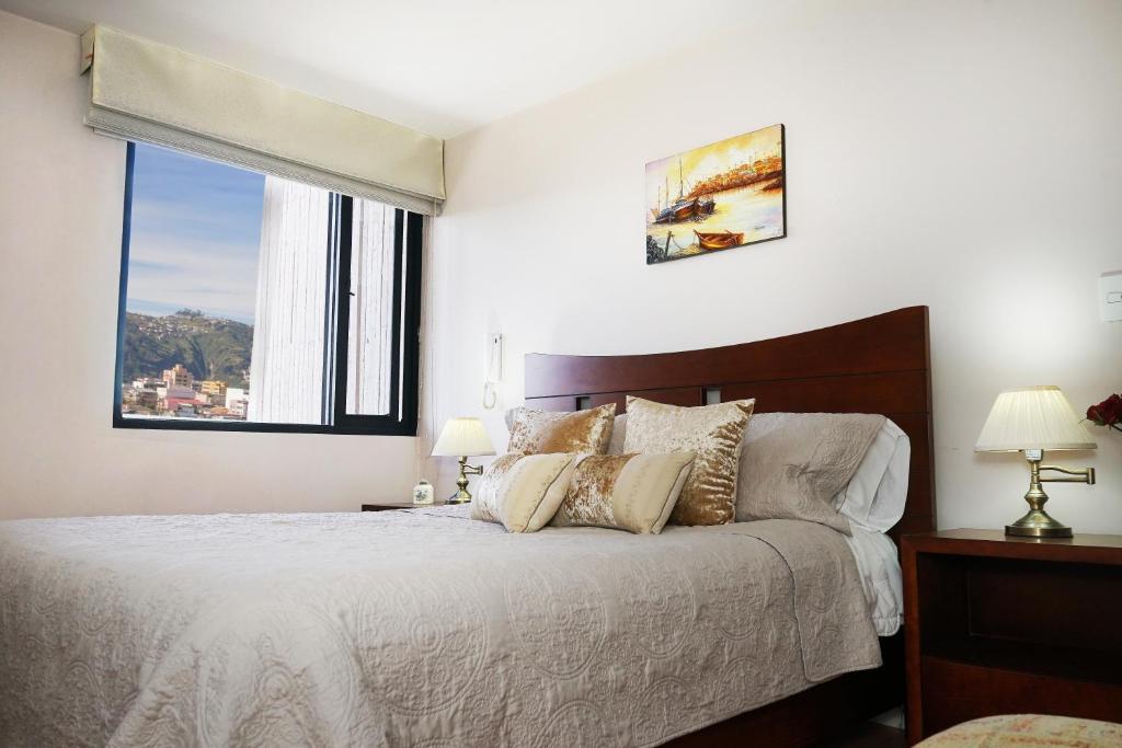 a white bedroom with a large bed with a window at Vega Apartment for Rent in Quito
