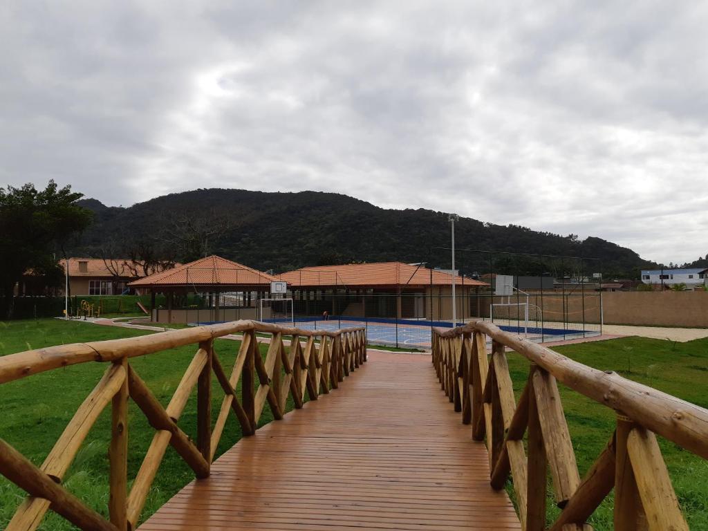 un puente de madera sobre una pista de tenis con un edificio en Cond. Vista Atlântico, en Itapema