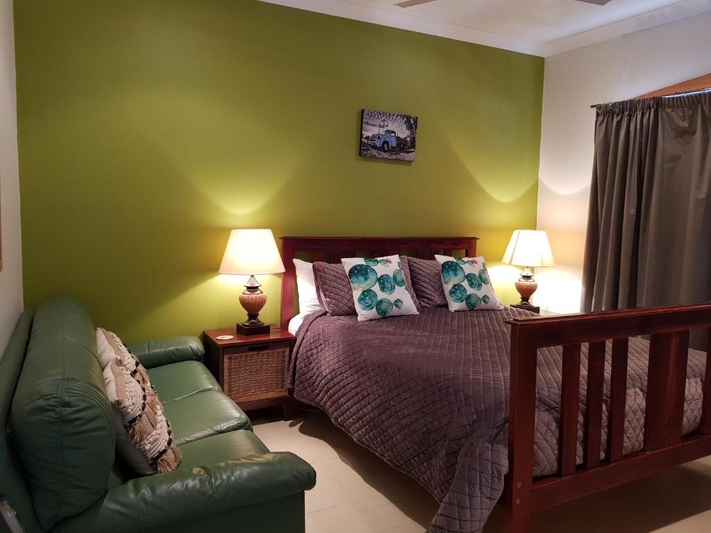Dormitorio verde con cama y sofá en Sonja's Bed and Breakfast, en Lightning Ridge