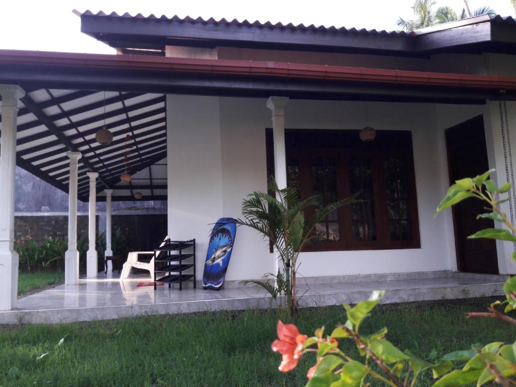 a patio of a house with two chairs and a porch at Mango Villa in Hikkaduwa