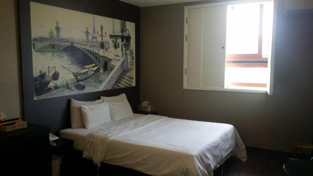 a bedroom with a bed with a picture on the wall at Rampart Hotel in Gwangmyeong