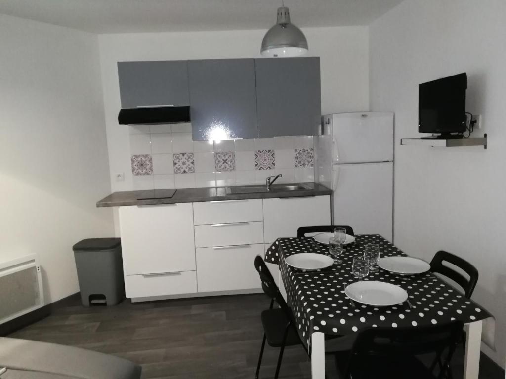 een keuken met een tafel met vier stoelen en een koelkast bij Appartement à 500m de la plage in Mèze