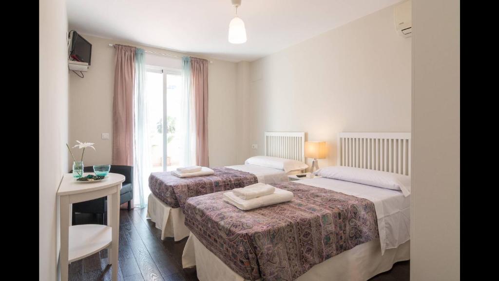 - une chambre avec 2 lits, un bureau et une fenêtre dans l'établissement Kentia Rooms, à Malaga