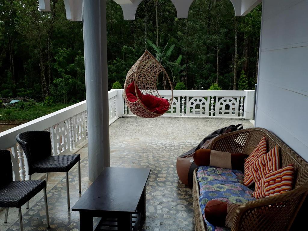 eine Veranda mit zwei Stühlen, einem Sofa und einer Schaukel in der Unterkunft Bluebell homestay in Chikmagalur