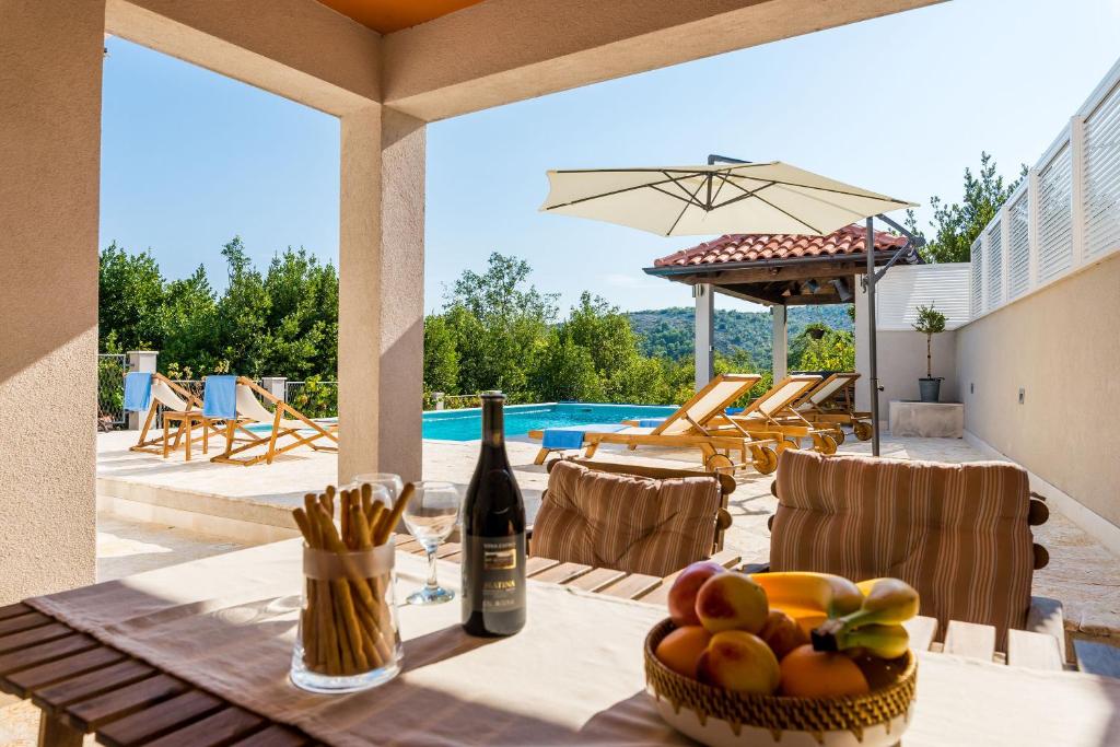 a table with a bottle of wine and a bowl of fruit at Villa Doli - Lovely holiday home with private pool in Doli