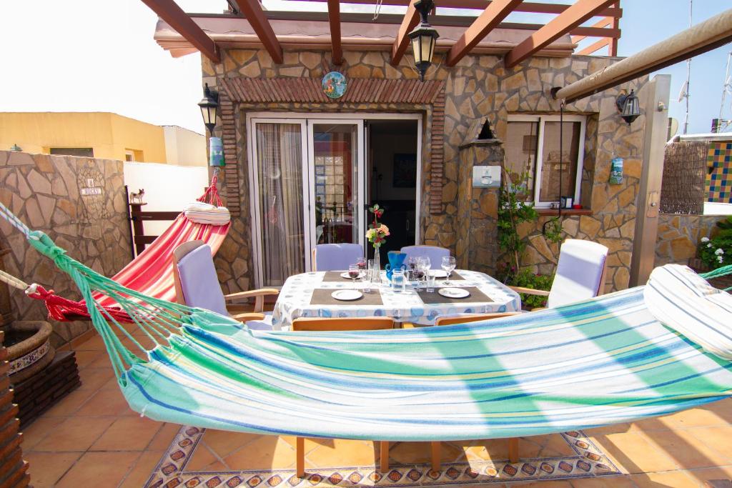 eine Hängematte auf einer Terrasse mit einem Tisch und Stühlen in der Unterkunft Apartamento Yaiza in Nerja