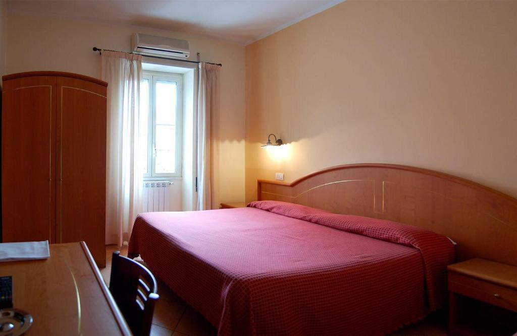 a bedroom with a red bed and a window at Hotel Ristorante Benigni in Campagnano di Roma