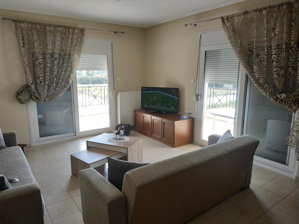 a living room with a couch and a tv and windows at Apartment Next to Coast in Nea Anchialos