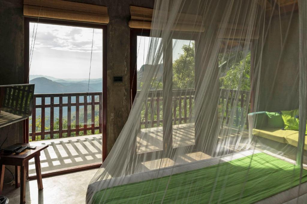 1 dormitorio con hamaca y balcón con vistas. en Roseland Cottages, en Bandarawela