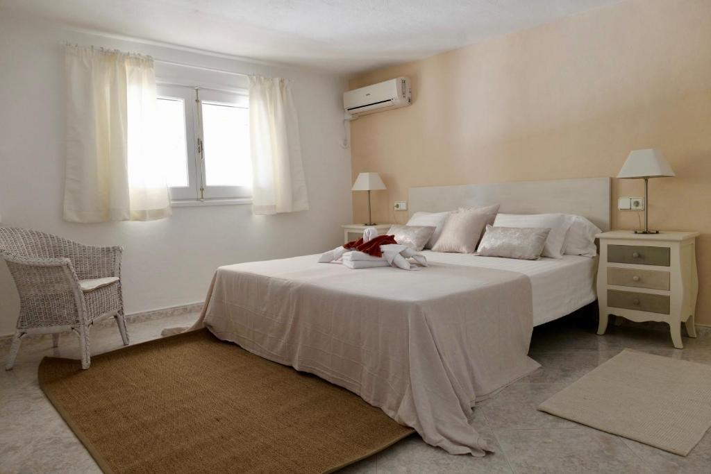una camera con un letto bianco e una finestra di Hacienda Encanto del Rio a Playa d'Es Figueral