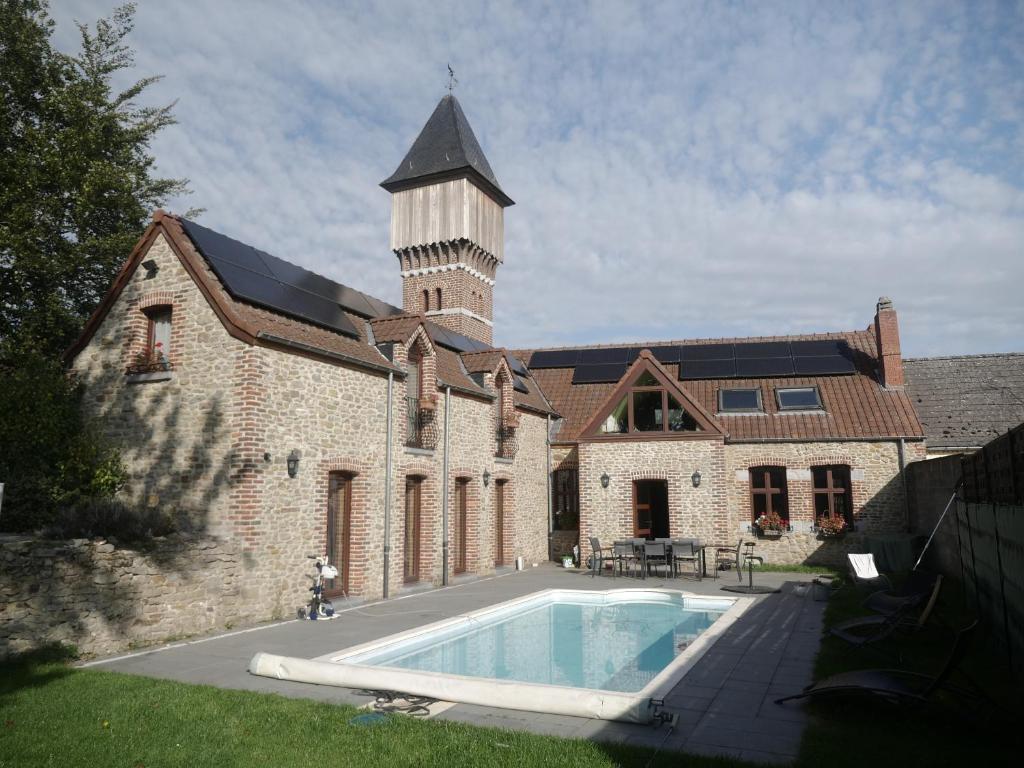a large brick building with a swimming pool and a water tower at Gite 3 épis Tour de Charme in Péruwelz