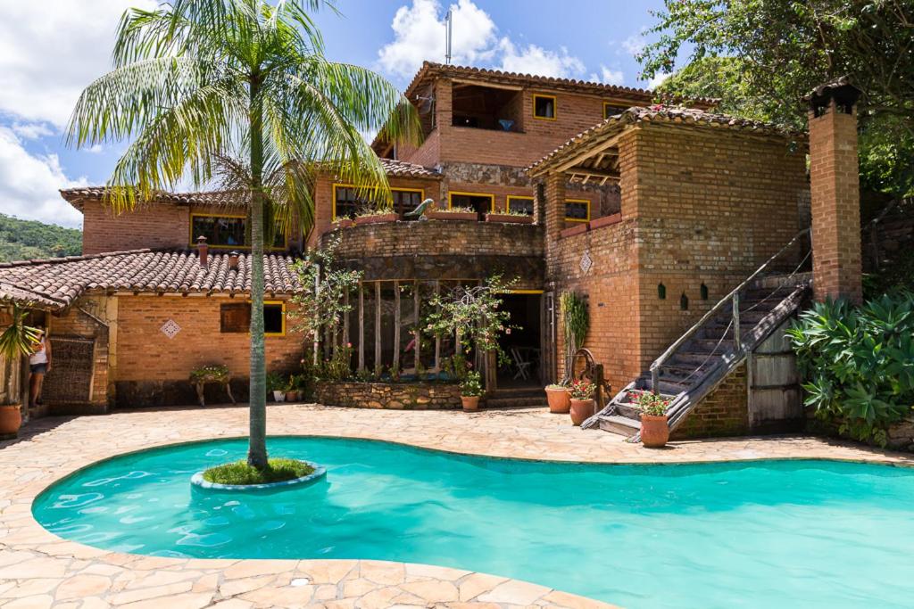 a house with a palm tree in front of it at Repousada Chalés in Conceição da Ibitipoca