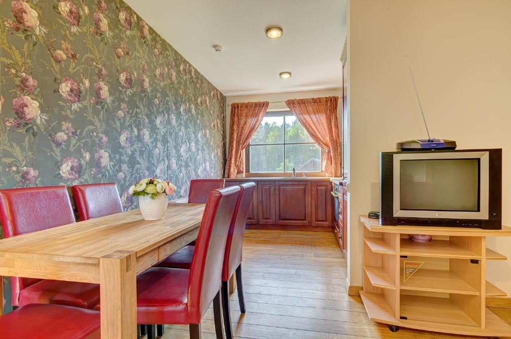 une salle à manger avec une table en bois et une télévision dans l'établissement Spacious Villa with Large Hall, à Mindūnai