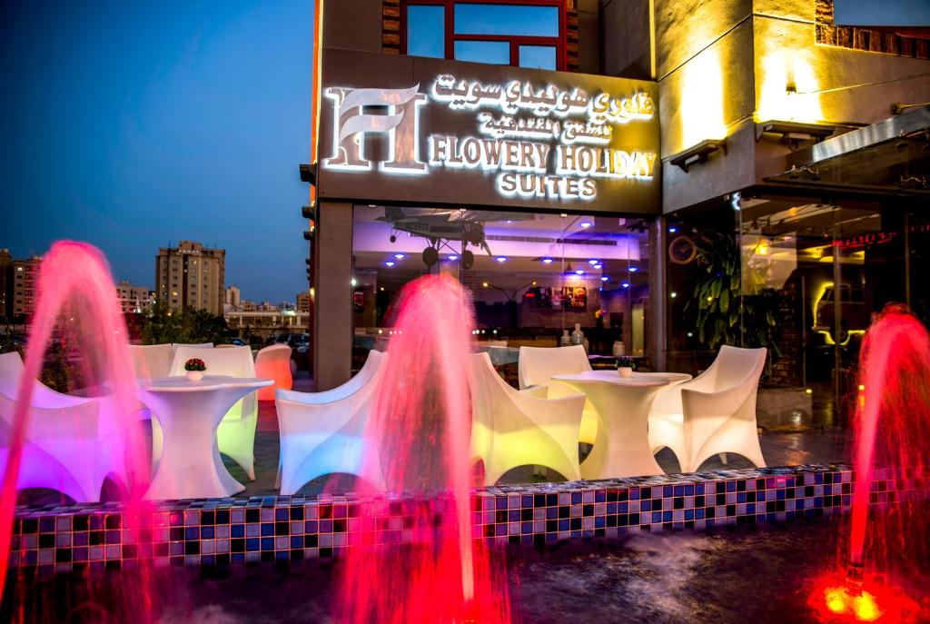 a fountain in front of a restaurant with tables and chairs at Flowery Holiday Suites in Kuwait