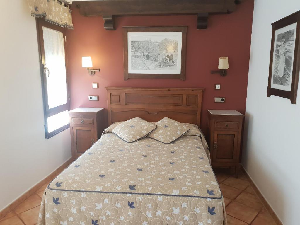 una camera con un letto in una stanza con pareti rosse di Hospedería Ana Pilar a Porcuna