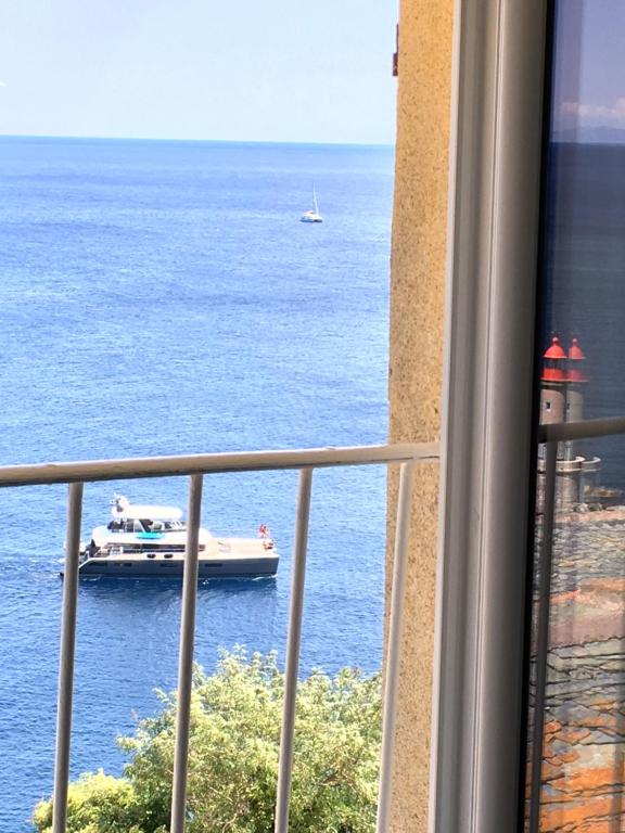 una vista su una barca in acqua da un balcone di Appartement Casaluna - Casadibastia - Vue mer Citadelle a Bastia