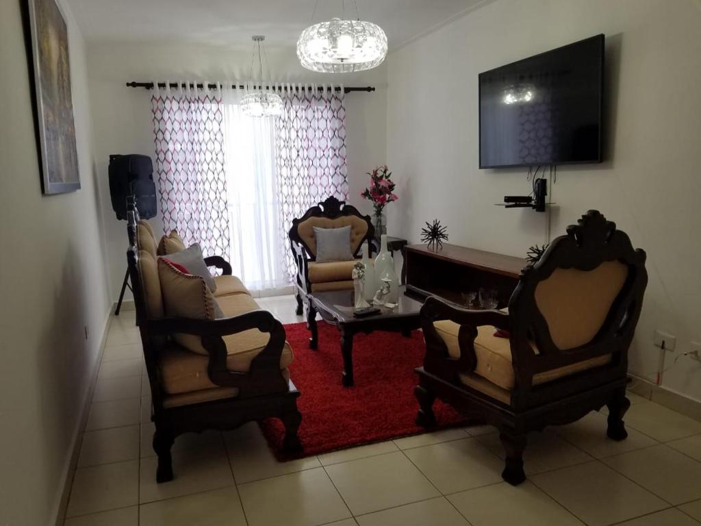 - un salon avec des chaises, une table et une télévision dans l'établissement Aprtamento Deluxe Santiago, Residencial Palma Real R402, à Santiago de los Caballeros