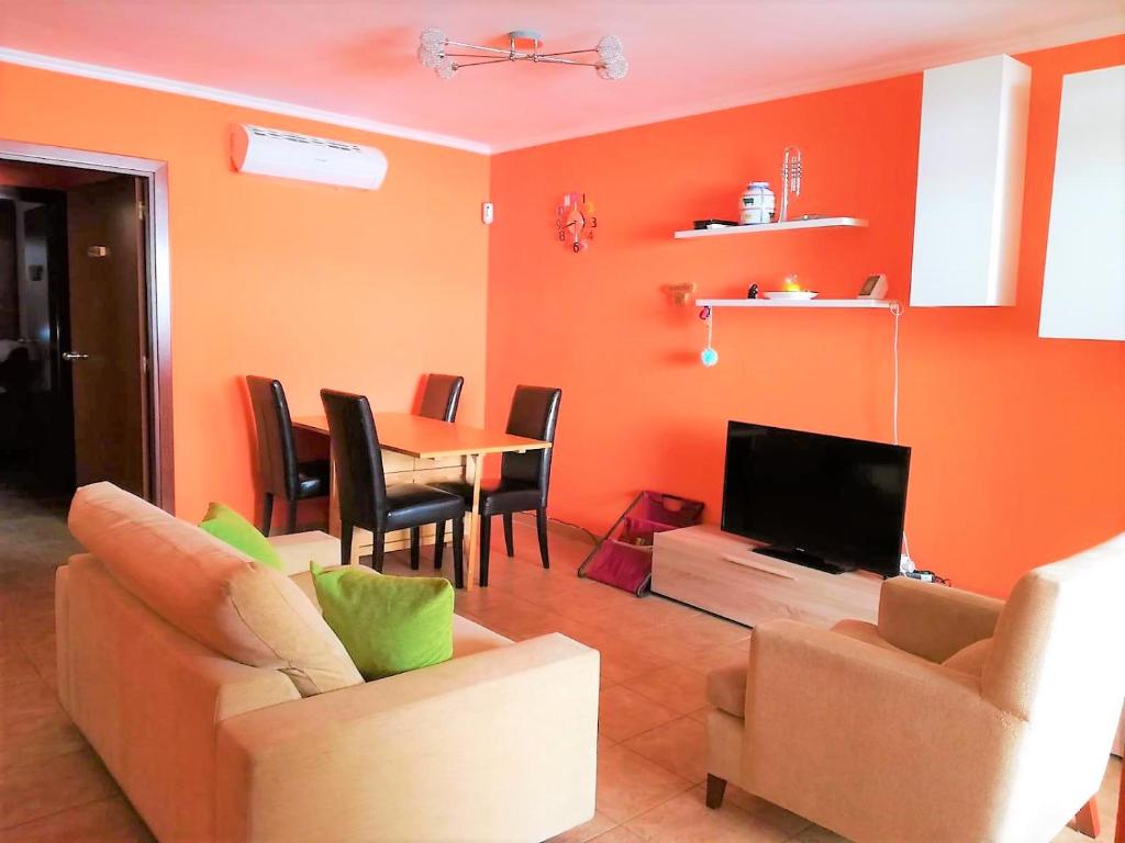 サロウにあるAmazing Cap Salou Apartmentのオレンジ色の壁のリビングルーム(テーブル、椅子付)