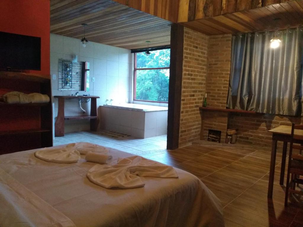 Schlafzimmer mit einem Bett, einer Badewanne und einem Fenster in der Unterkunft Pousada Pizzaria do Vale in Visconde De Maua