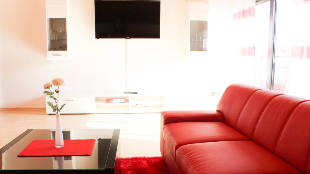 ein Wohnzimmer mit einem roten Sofa und einem Tisch in der Unterkunft Ferienwohnung-Fuchs in Bad Schonborn