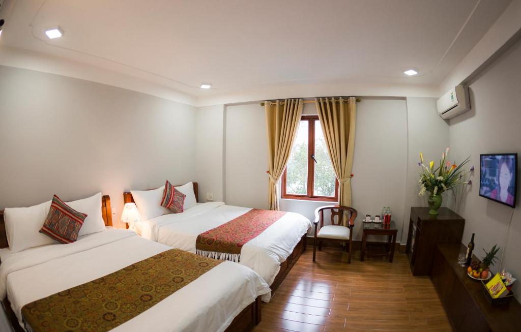 Una habitación de hotel con dos camas y una ventana. en Sapa Land Hotel, en Sa Pa