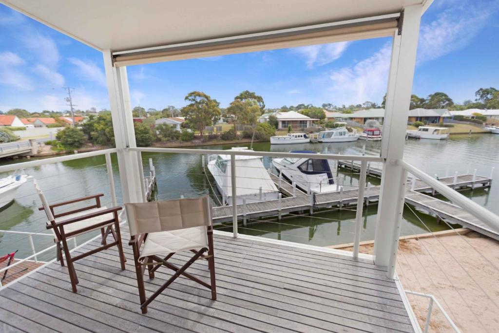 a balcony with a table and a chair and a marina at Beach 2 in Paynesville