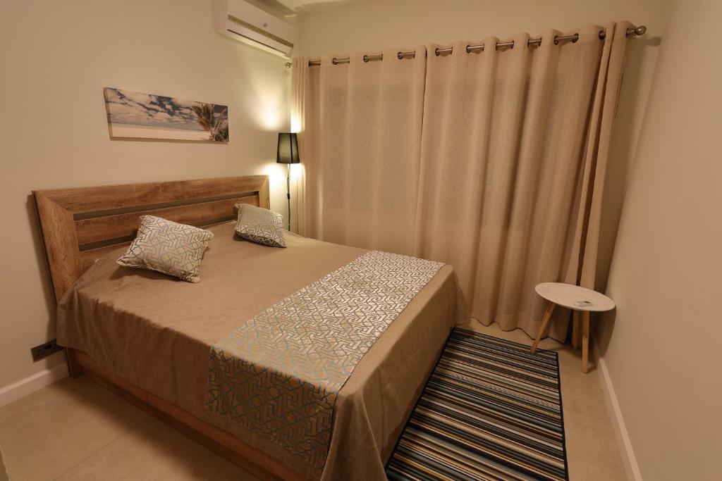 a small bedroom with a bed with a curtain at Beach Cove 4 in Pereybere