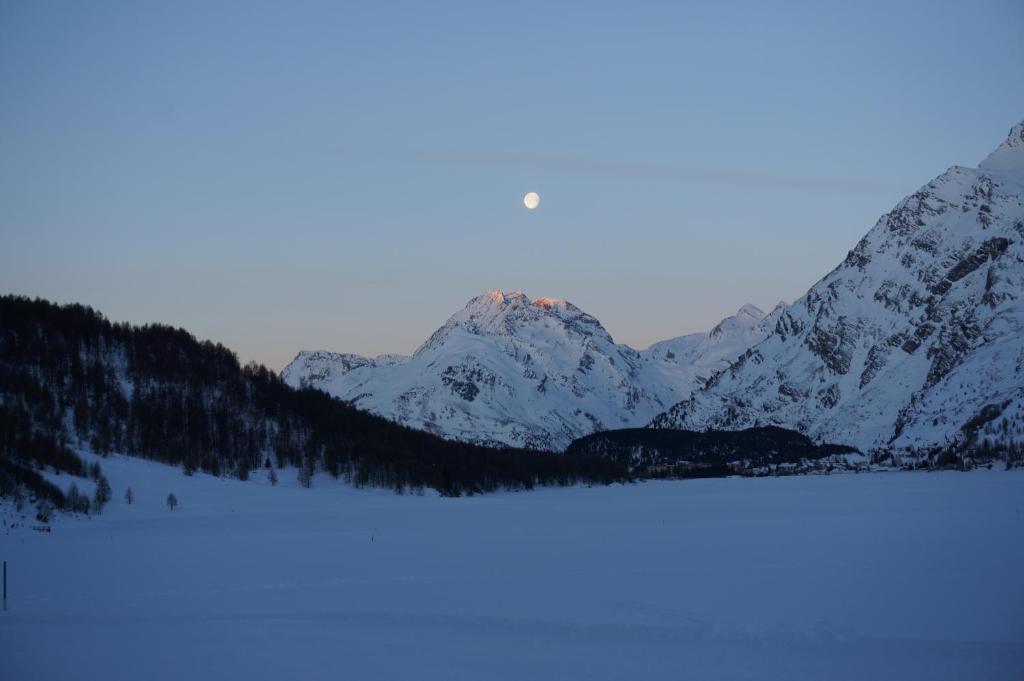 马洛亚Hotel Ristorante Lagrev的山前有湖,有雪覆盖