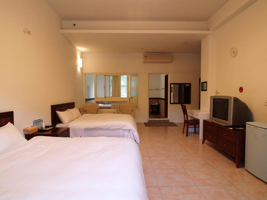 a hotel room with two beds and a television at Dainty Spa Hotel in Taimali