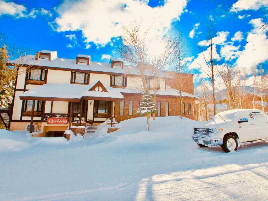 八幡平市的住宿－安比美麗人生賓館，雪中停在房子前面的白色汽车