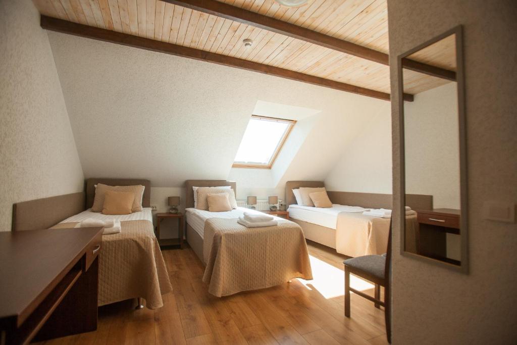 a attic room with two beds and a window at Central Hotel Radviliškis in Radviliškis