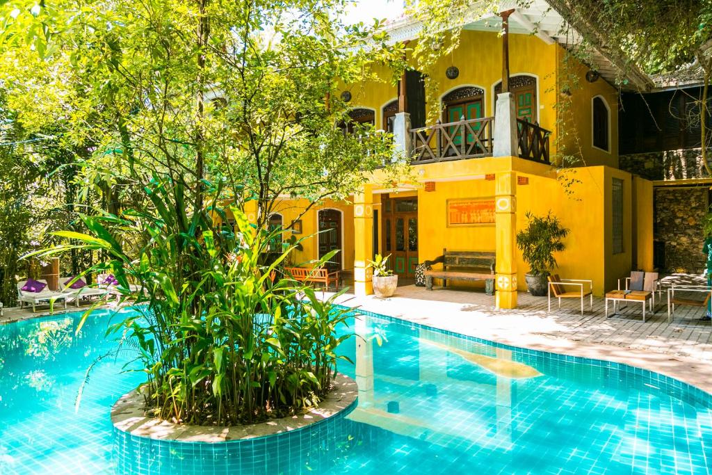 - une piscine en face d'une maison jaune dans l'établissement Thambapanni Retreat, à Unawatuna