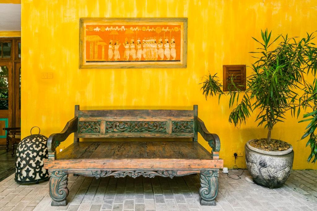 a wooden bench sitting in front of a yellow wall at Thambapanni Retreat in Unawatuna