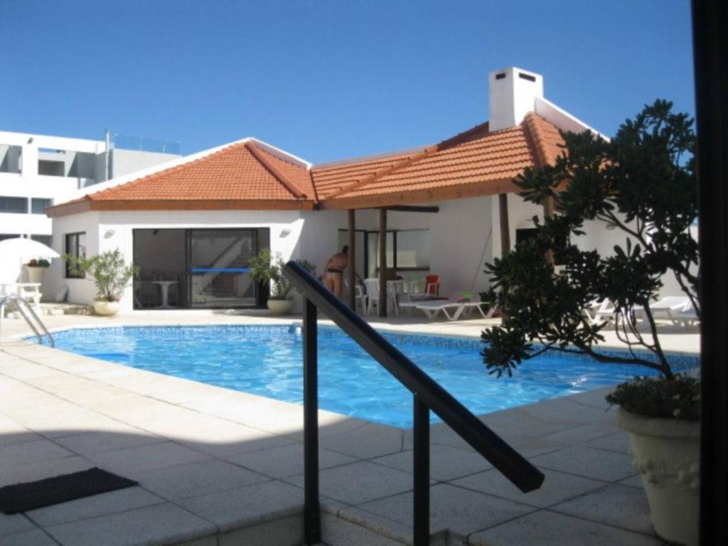 uma piscina com um guarda-sol ao lado de um edifício em Apartamento con todo incluido casi Gorlero em Punta del Este