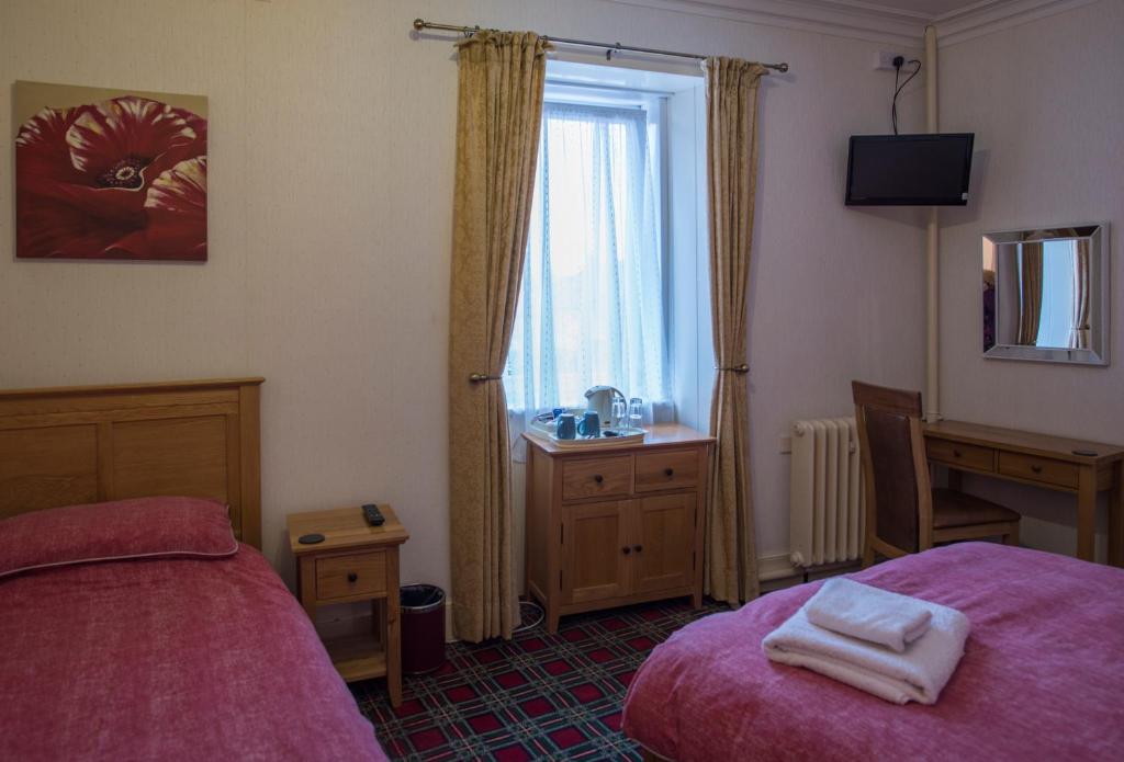 1 dormitorio con cama, escritorio y ventana en Heather Glen Guest House, en Elgin