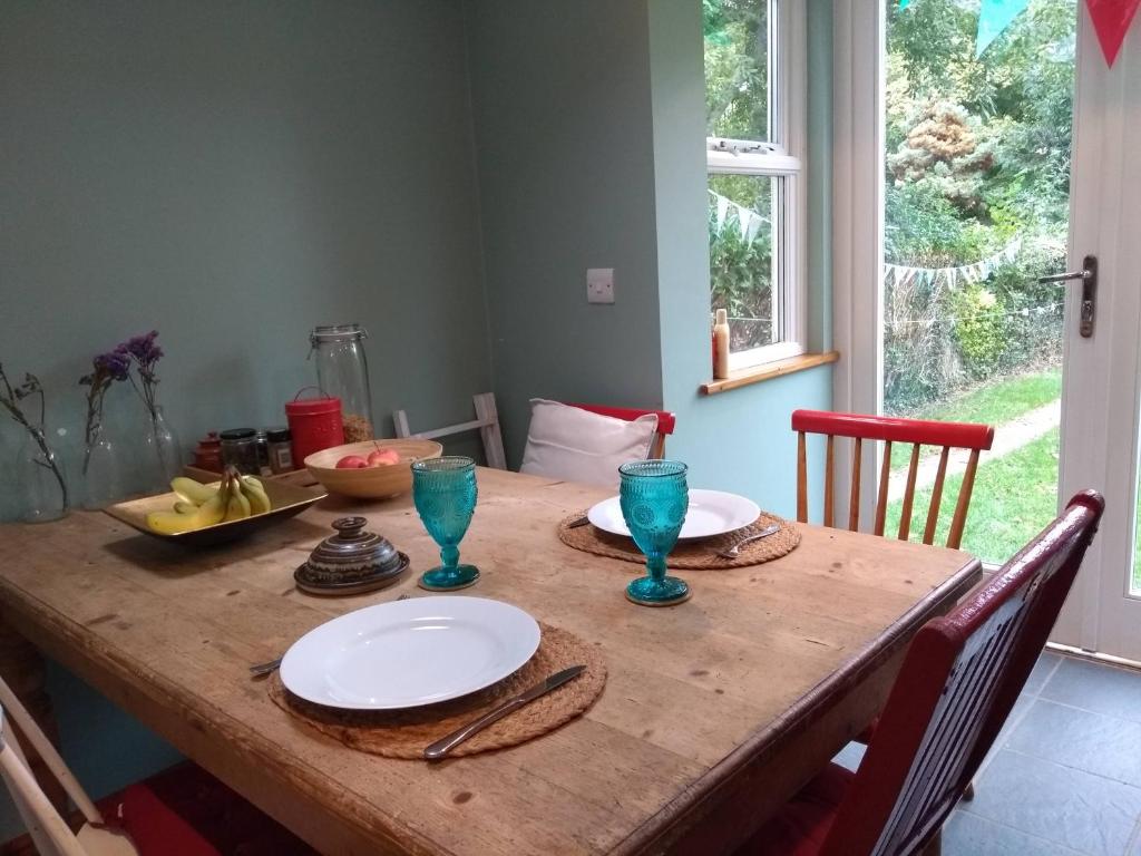 a wooden table with plates and glasses on it at Lovely Terraced 2-Bed House (near Hinksey Park) in Oxford