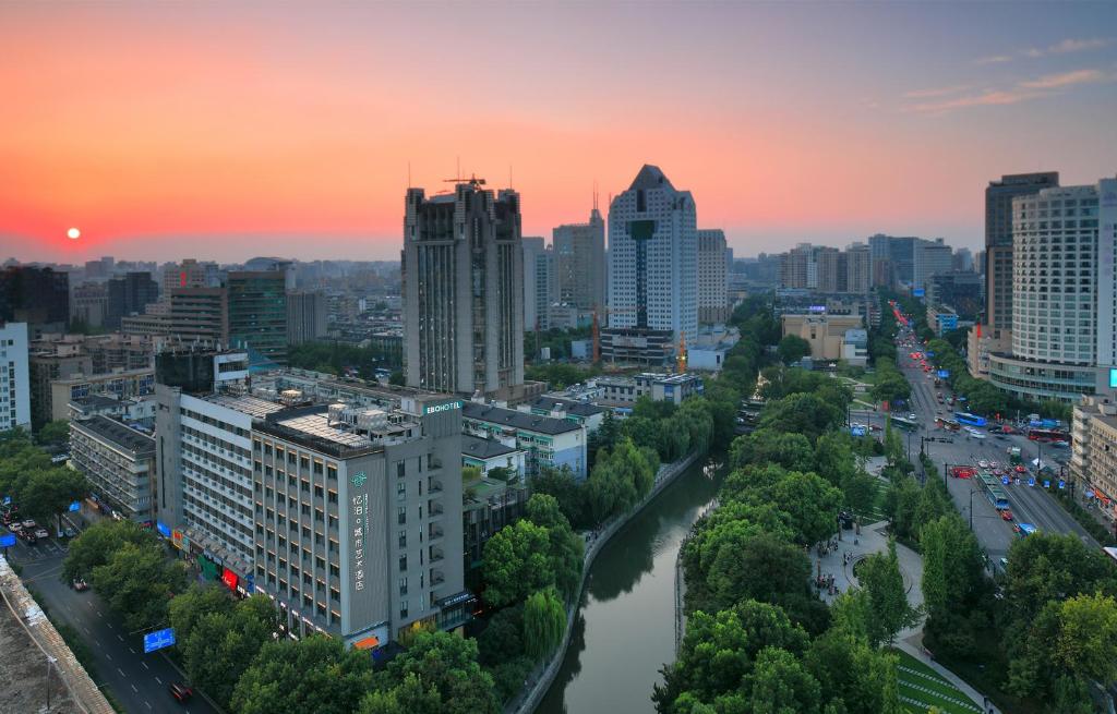 a city skyline at sunset with a river and buildings at EBO Hotel Hangzhou Wulin in Hangzhou