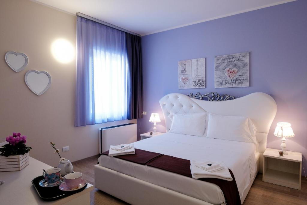 una camera con un letto bianco e una grande finestra di Albergo Trattoria Italia a Desenzano del Garda