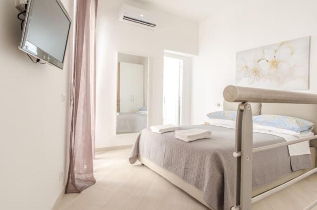 1 dormitorio blanco con 1 cama y TV de pantalla plana en Lea's House independent solution, en Nápoles