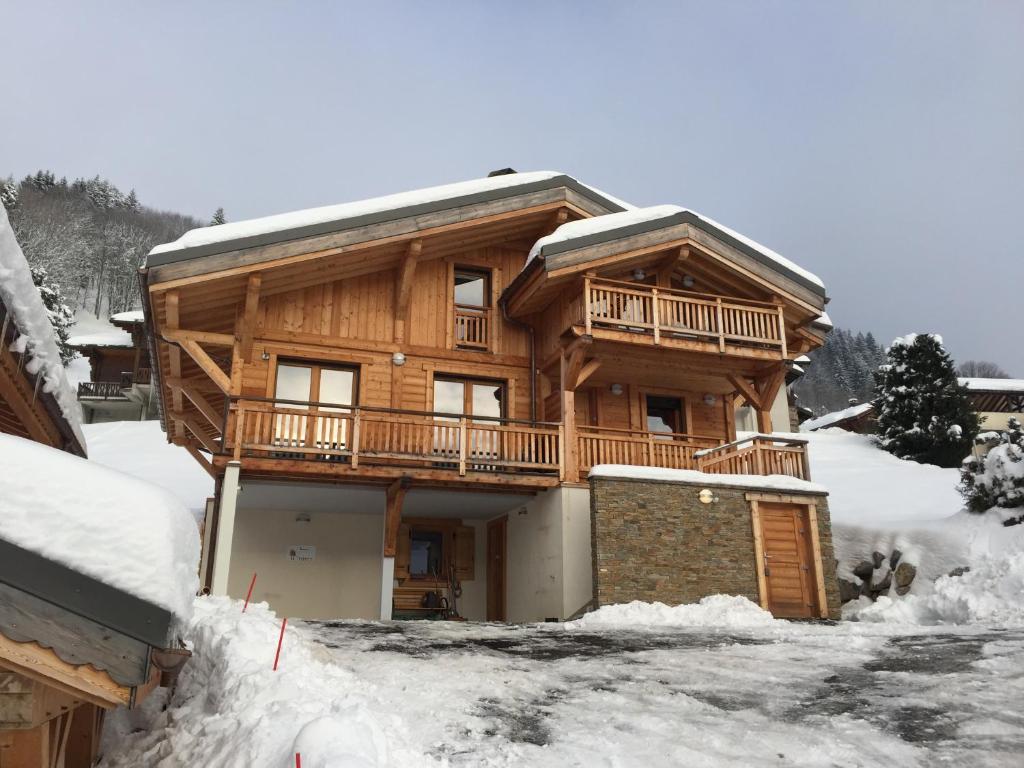 uma cabana de madeira na neve com uma entrada em ORTA Chalet em Les Gets