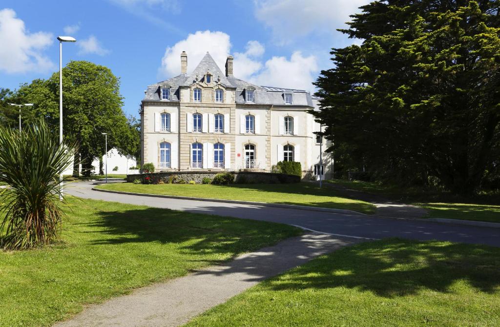 een groot wit huis met een weg ervoor bij Résidence Néméa Le Domaine de la Baie in Audierne