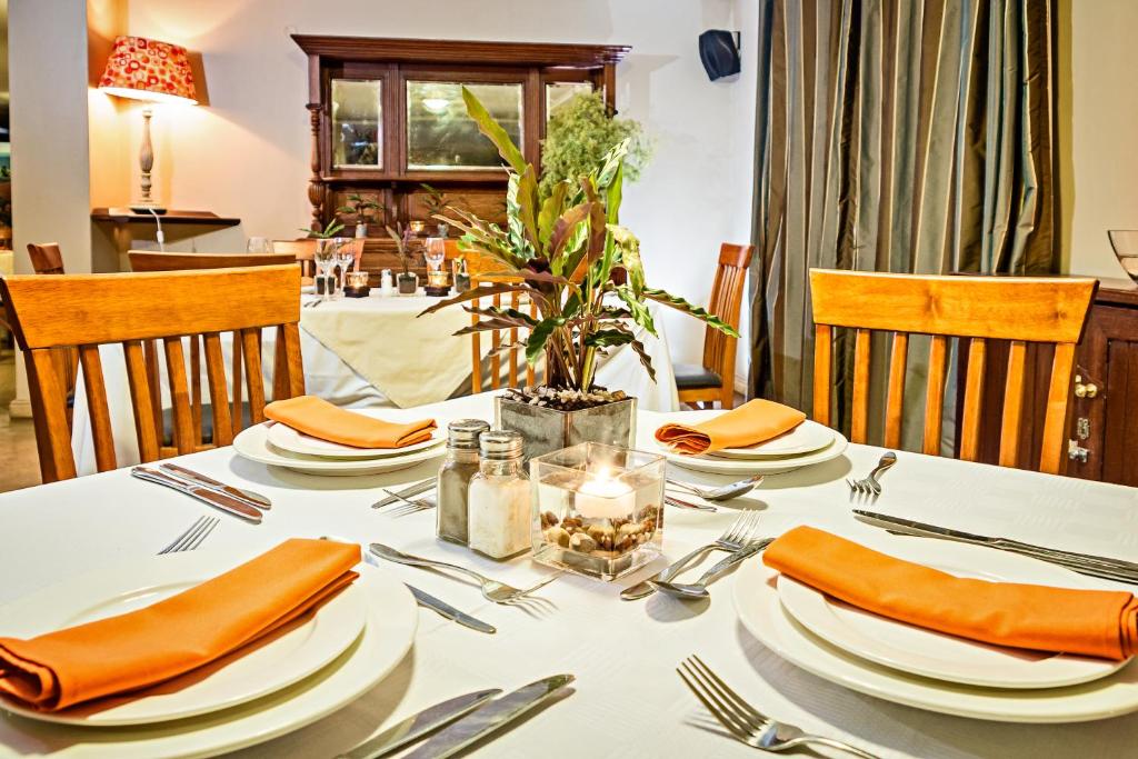 a dining room table with a white tablecloth and orange napkins at Nolangeni Hotel in Kokstad