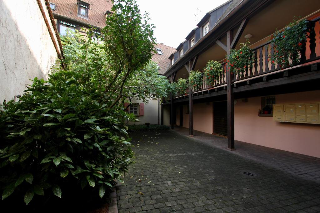 an alley in a building with trees and plants at Hotel Restaurant Le Maréchal - Teritoria in Colmar