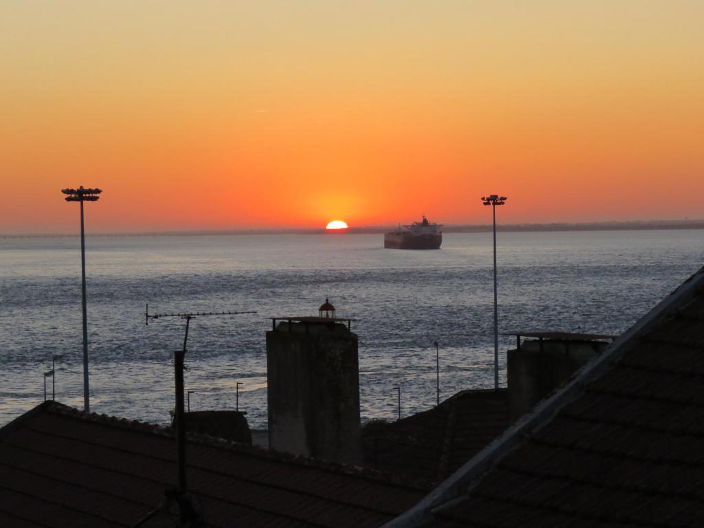 Una puesta de sol sobre el océano con un barco en el agua. en TEJO HOUSE RIVER Lisbon (Cacilhas), en Almada