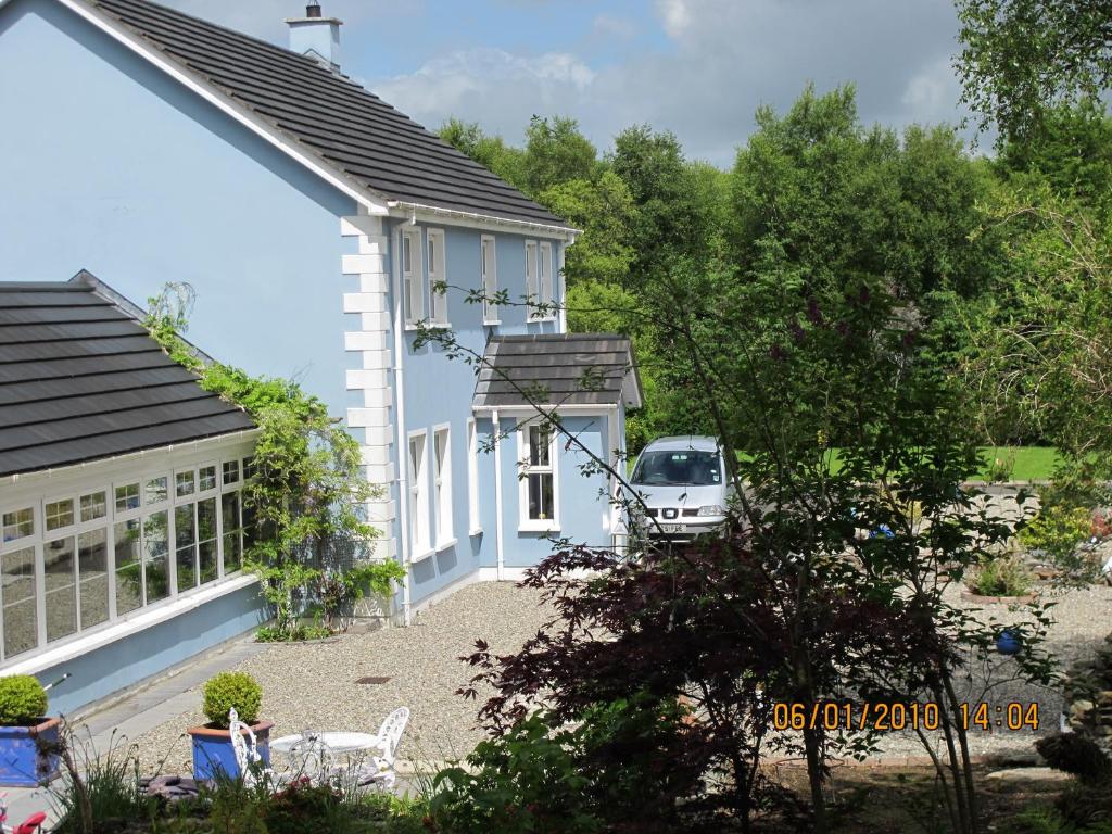 ein weißes Haus mit einem Auto auf dem Hof in der Unterkunft Five Oaks in Derry Londonderry