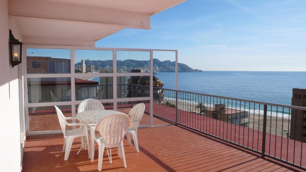 balcón con mesa, sillas y vistas al océano en Apartamentos Nere, en Benidorm