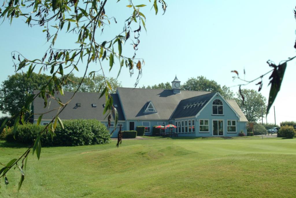 a large blue house with a green yard at Richmond Park Golf Club in Watton