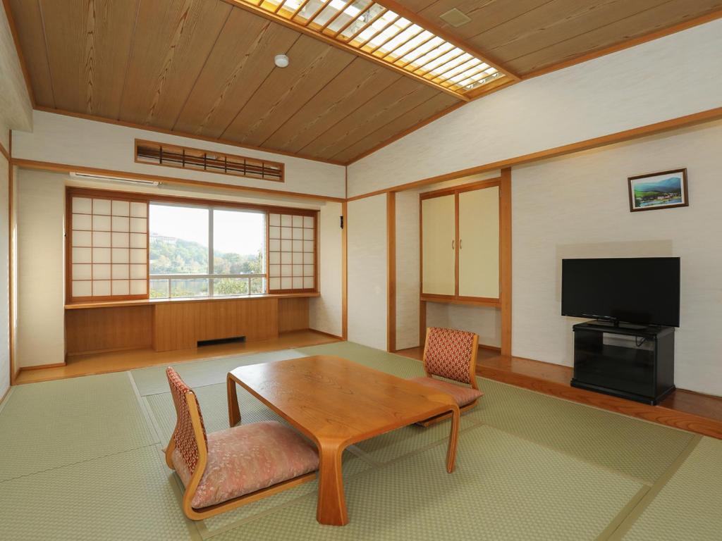 een kamer met een tafel en stoelen en een televisie bij Shirakabako View Hotel in Tateshina